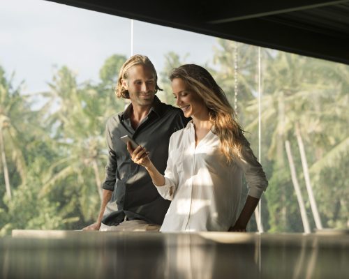 Smiling couple with smartphone in design house